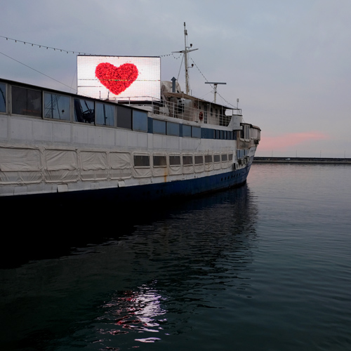 Boat at dusk with illuminated heart on screen in Rijeka, Croatia
